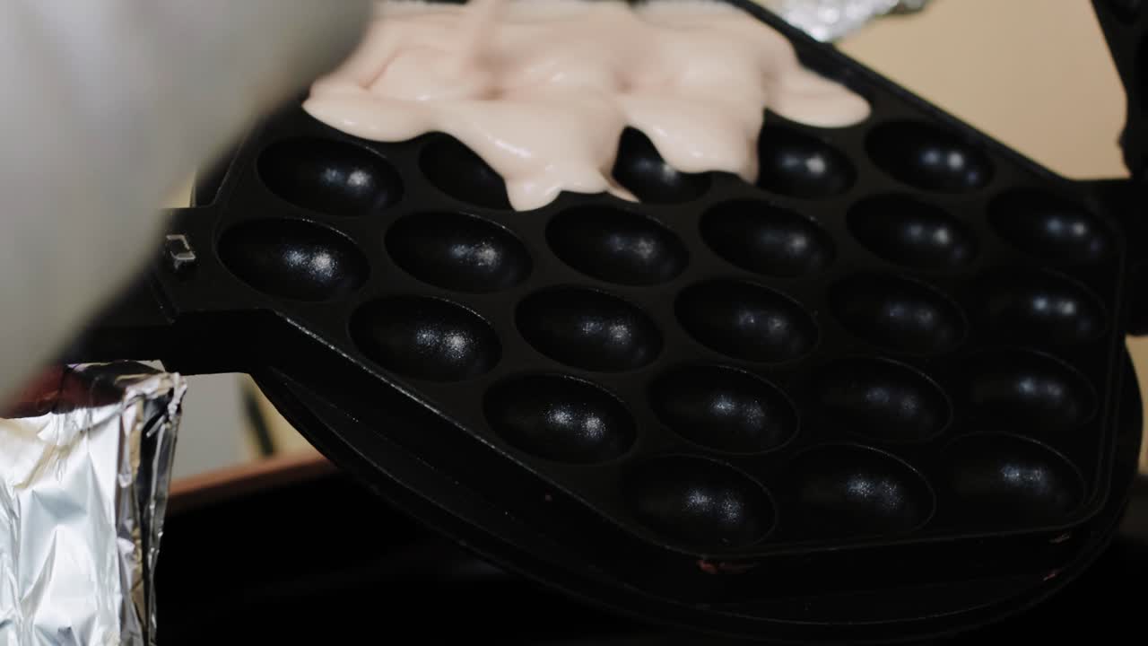 와플 토스터에 와플 혼합물을 붓는 사람