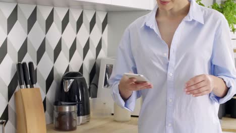 Mujer-Preparando-Café-Por-La-Mañana-Y-Usando-Un-Teléfono-Móvil