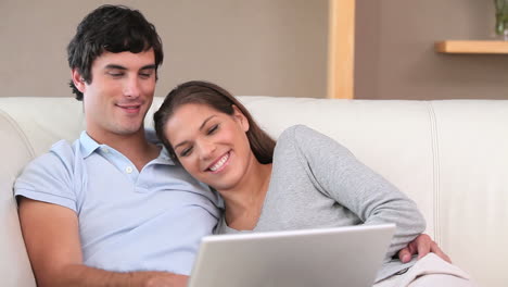 pareja sonriente usando una computadora portátil