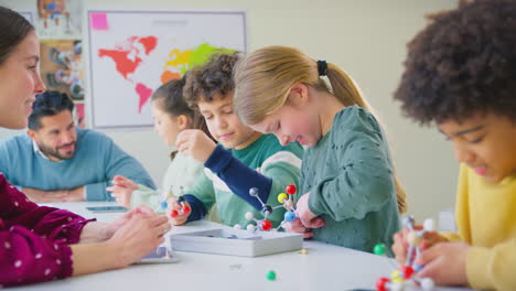 multi-cultural students with teachers in classroom studying molecular model in science class