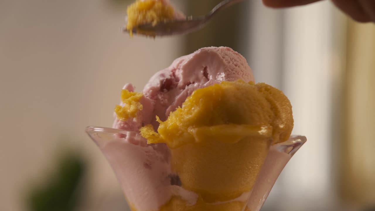 A man hand holding a spoon while eating delicious and tasty ice cream from a glass cup. Summer and sugar concept.