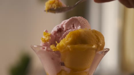 a man hand holding a spoon while eating delicious and tasty ice cream from a glass cup. summer and sugar concept.