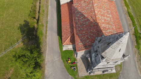 aerial view of three backpackers taking a rest lying on grass near an ancient church 1