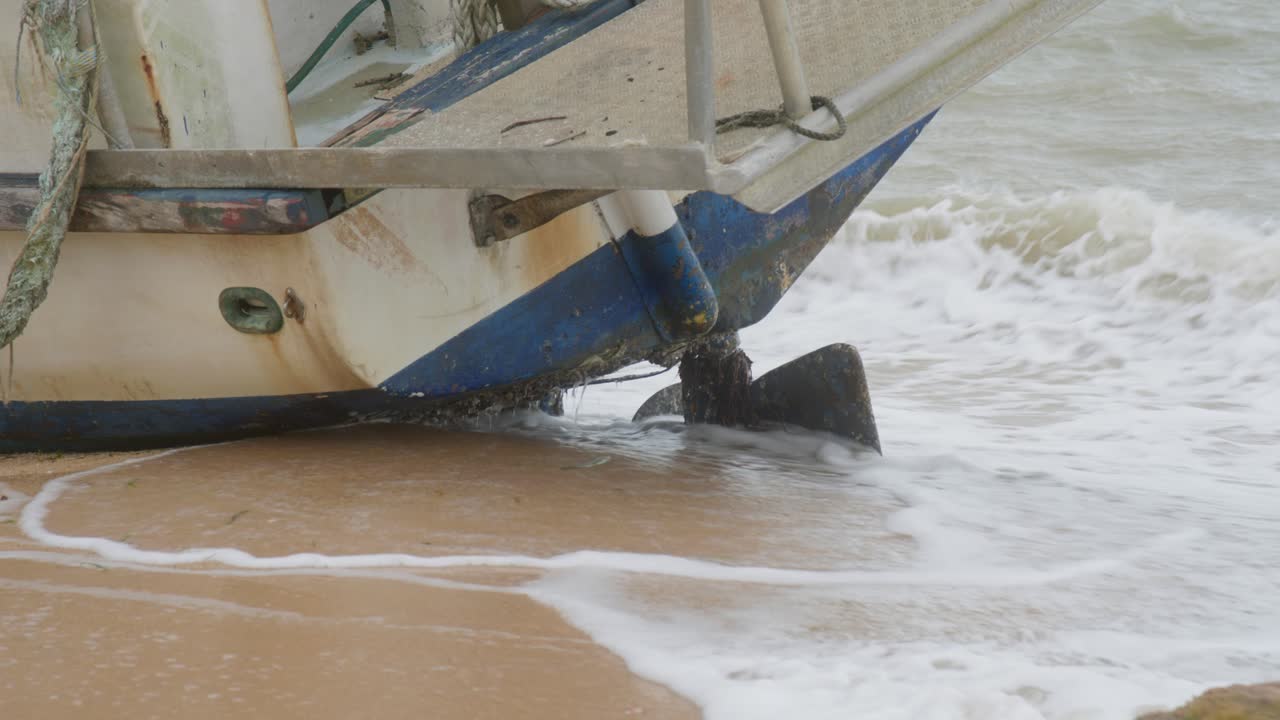 Un peschereccio commerciale, spinto su una spiaggia remota da recenti e forti tempeste monsoniche, ora giace su un fianco. Poppa lato sinistro, clip 6.