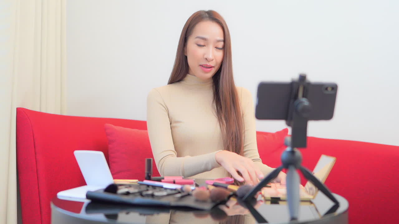 bonita vloguera asiática grabando vlog sobre productos de maquillaje de belleza para el cuidado de la piel con smartphone