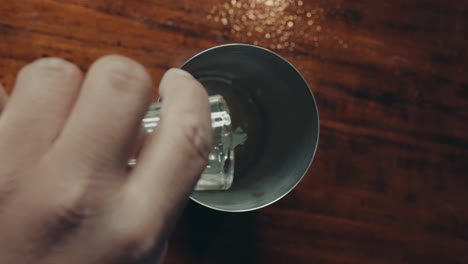 top down view of bartender's hand adding lime juice into metal cocktail shaker, full frame