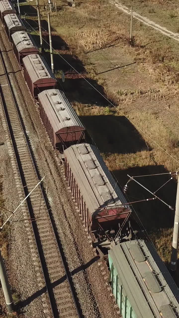 freight train is passing a highway. Aerial view of the freight train with wagons Vertical video