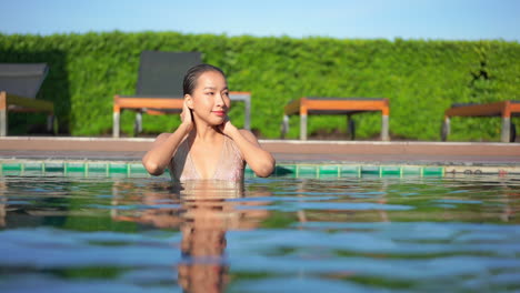 Una-Atractiva-Joven-Saludable-En-Una-Piscina-Alisa-Su-Cabello-Mojado-Y-Luego-Camina-Hacia-La-Cámara