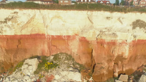 pullback aerial drone shot from closeup of old hunstanton orange and white cliffs with small sandy and rocky beach north norfolk uk