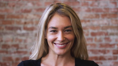 portrait of smiling caucasian woman standing against brick wall in coffee shop