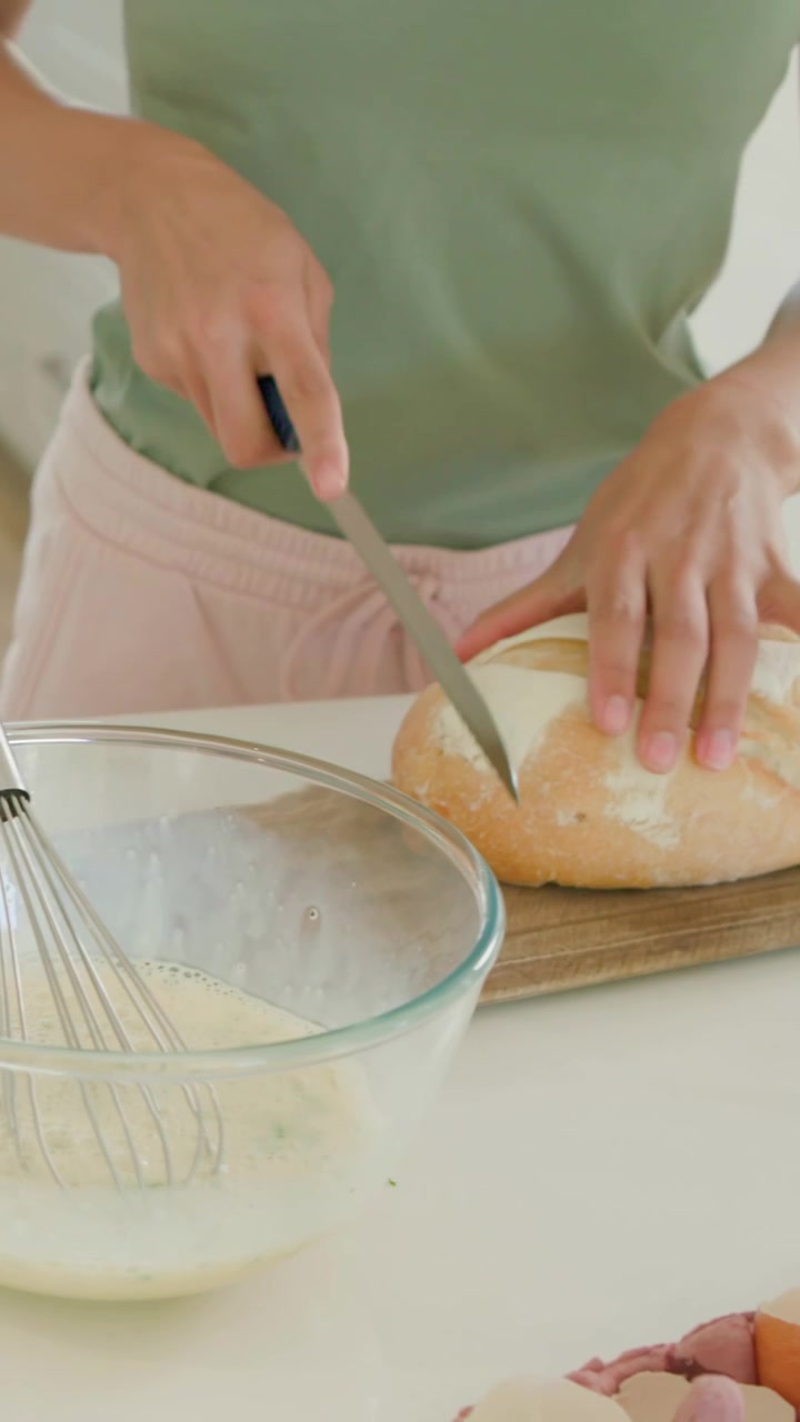 Vertical video: Whisking cook green top with bowl until foaming, slicing bread for meal at home