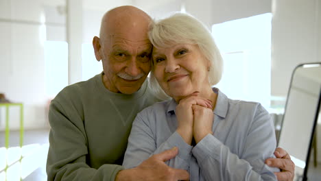 senior couple hugging and looking at camera in a studio