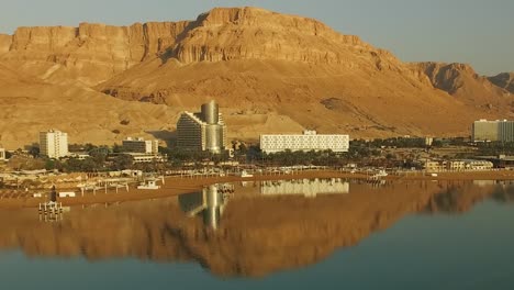 beach resort reflected by the dead sea with a huge mountain desert behind