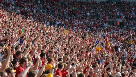 a sea of excitement: an enthusiastic crowd cheers with raised hands in a thriving sports arena, capturing the passion and energy of fans united for their team