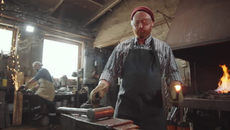 blacksmith taking hot metal from fire and hammering it on anvil