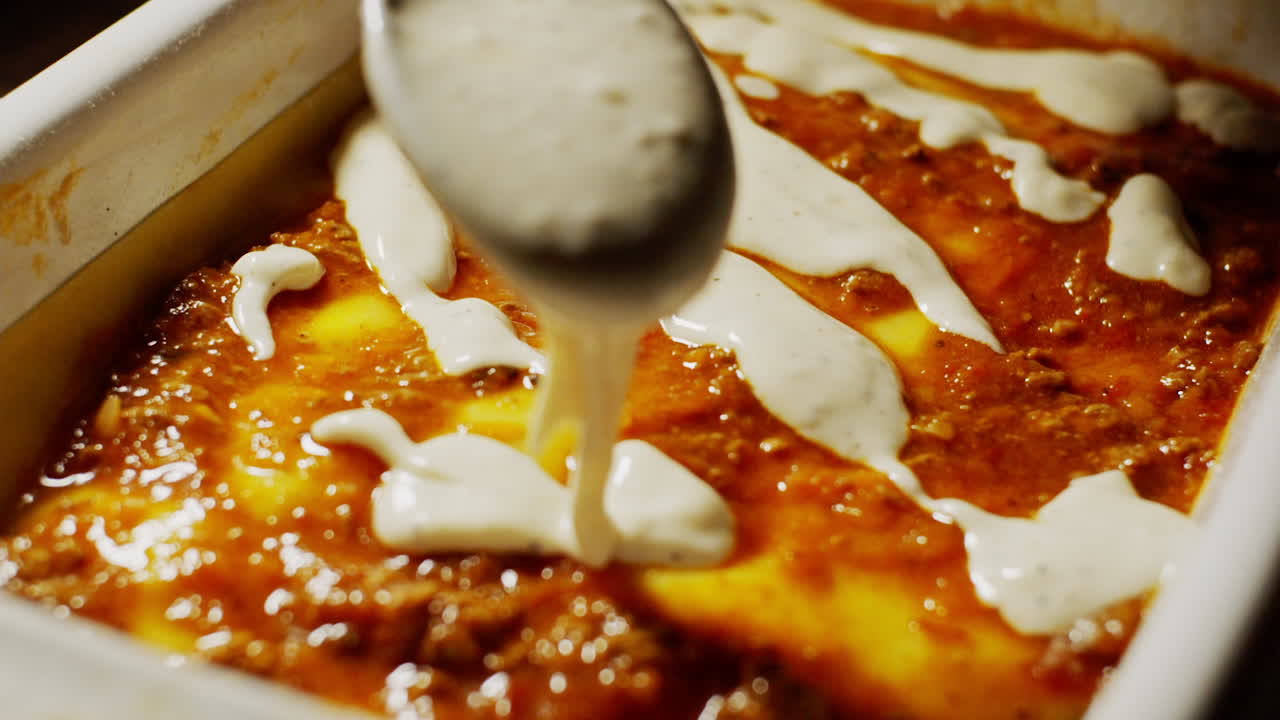 볼로네제 라자냐 위에 흰색 액체 베샤멜 소스를 붓고, 배경