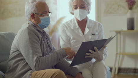 médico sosteniendo el clipboard con documentos y hablando con el paciente