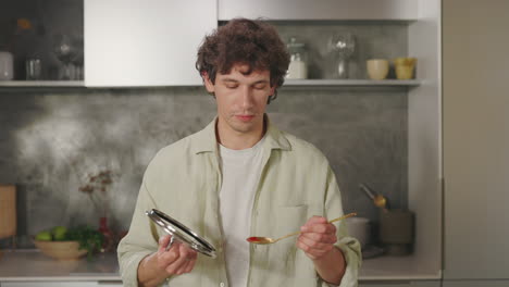 man tasting food while cooking in the kitchen