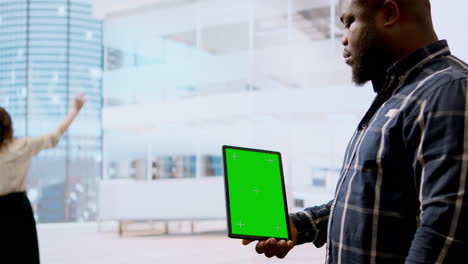real estate agents and client examine blueprints next to a green screen