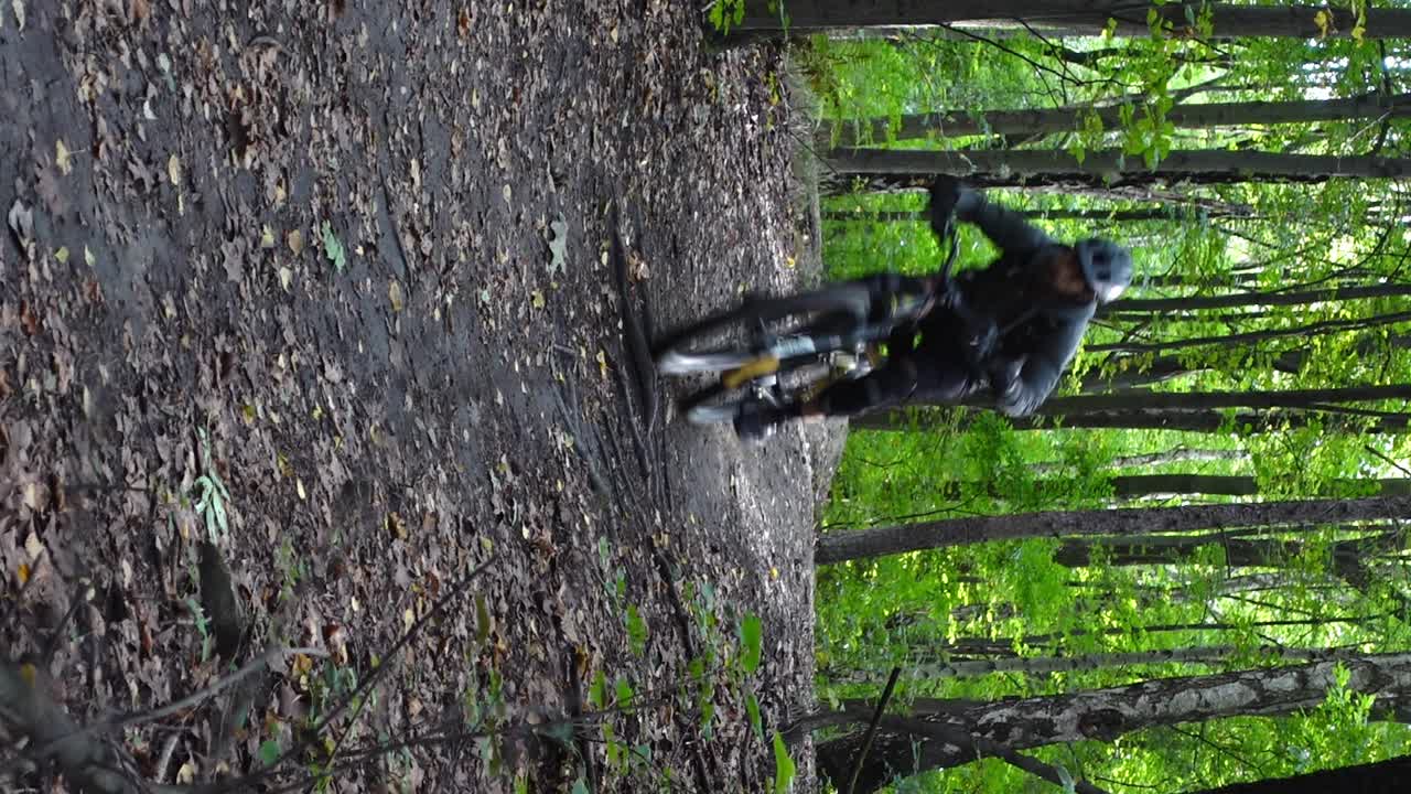 Vertical front shot of man jumping on electric bicycle in forest in slow motion