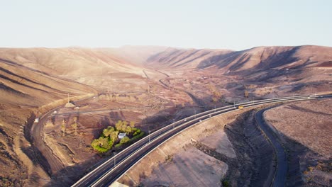 푸에르테벤투라 (fuerteventura) 의 건조한 언덕을 가로질러 휘어지는 길, 황금빛이 그림자를 던지는, 조용하고 고립된, 공중 풍경