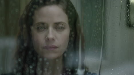 woman looking out rainy window