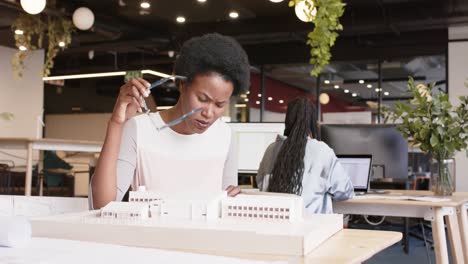 Thoughtful-african-american-female-architect-inspecting-architectural-model-at-work,-in-slow-motion