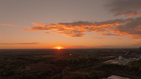 Aerial-wide-shot-gold-sunset,-sun-at-the-horizon-line,-golden-clouds,-HDR-4K50Fps