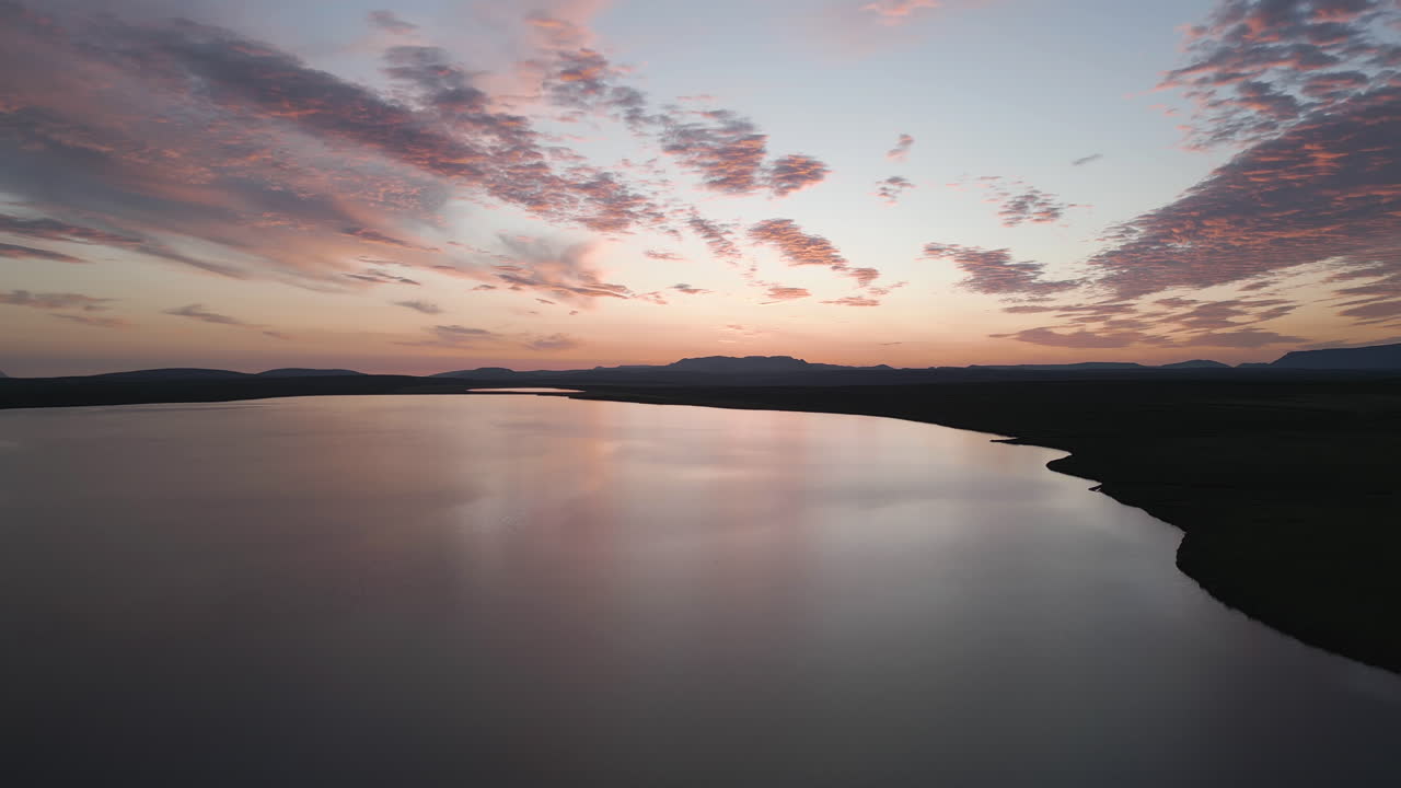 Sunset reflecting on calm lake water with colorful and glorious evening sky from above, Iceland