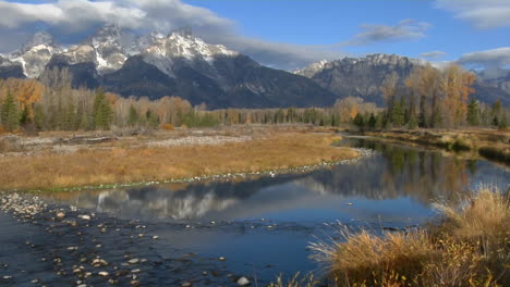 the grand teton mountains are reflected in a mountain river