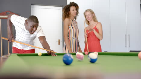 joven afroamericano juega al billar con mujeres biraciales y caucásicas
