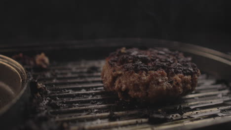 Hamburguesa-De-Carne-Cruda-O-Pollo-Con-Mucho-Humo-En-La-Parrilla-Preparada-Para-Un-Delicioso-Sándwich-De-Hamburguesa-Y-Luego-Retirada,-Con-Un-Fondo-Negro-Y-Una-Luz-Sencilla-Filmada-En-4k-Crudo