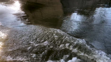 powerful water stream flowing under a bridge on a sunny day