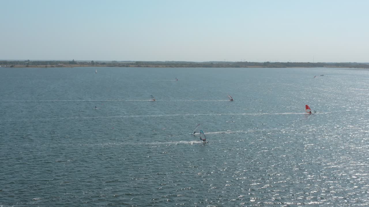 drone - toma aérea de muchos surfistas en un mar azul, ondulado y ventoso en un día soleado con nubes blancas en una isla, zelanda, países bajos, 25p