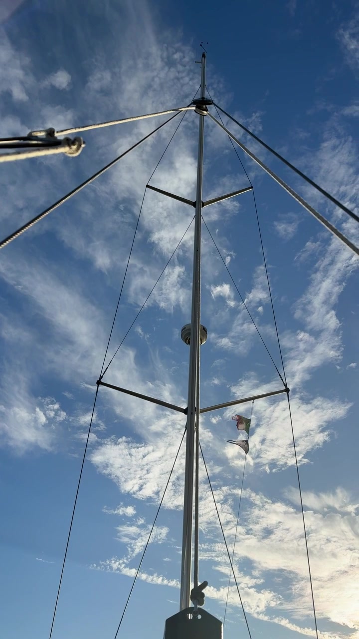 En parasailer driver nær en bådmast under en overskyet himmel – Lavvinkelbillede