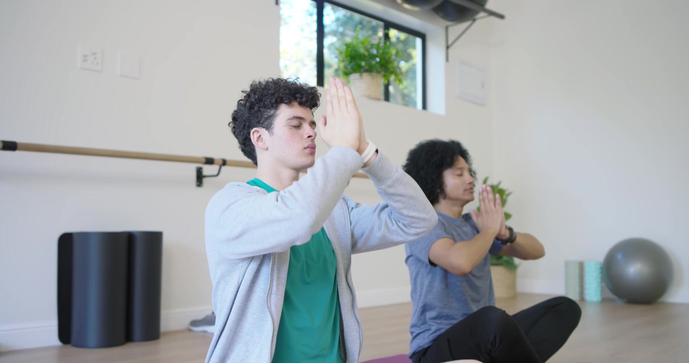 Two Young Men Practicing Yoga and Meditation in a Studio