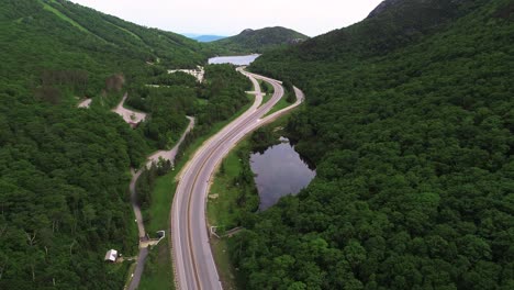 drone footage of scenic highway in nh white mountains with mountains, trees, and lake