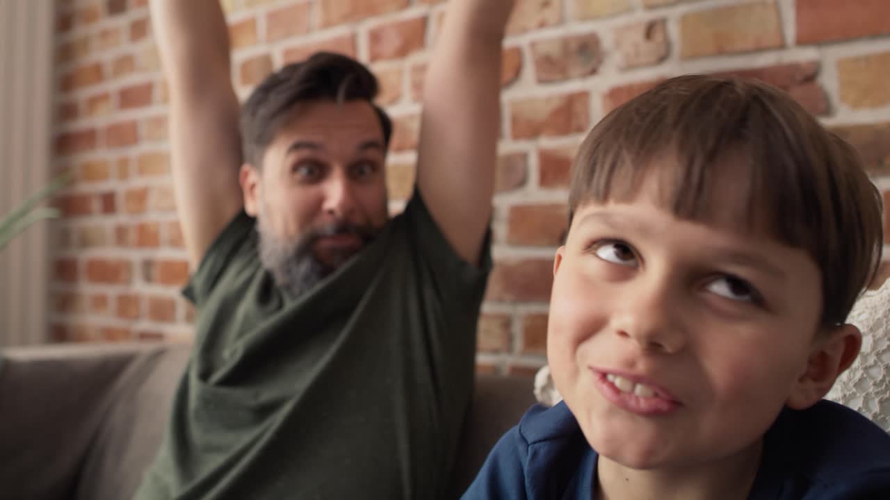 video de padre e hijo jugando un videojuego en el sofá