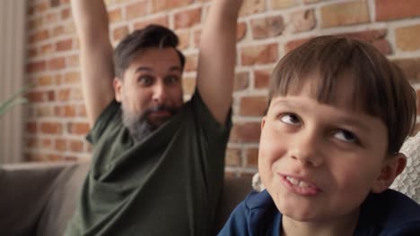 video de padre e hijo jugando un videojuego en el sofá