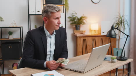 upset businessman freelancer counting dollar cash insufficient amount of money at home office desk