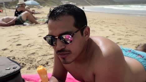 hombre hispano comiendo un cono de helado en la playa