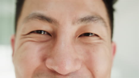 close-up of a young asian man's smiling face at home