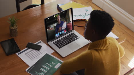 african american woman using laptop on video call with male colleague working from home