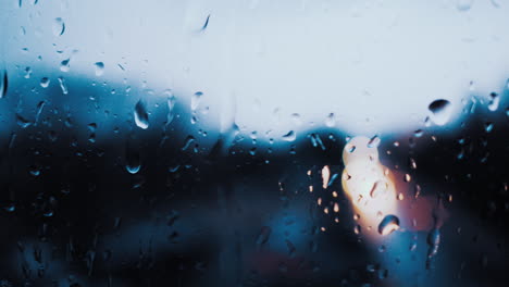 close up of a rain soaked window with traffic lights in the background