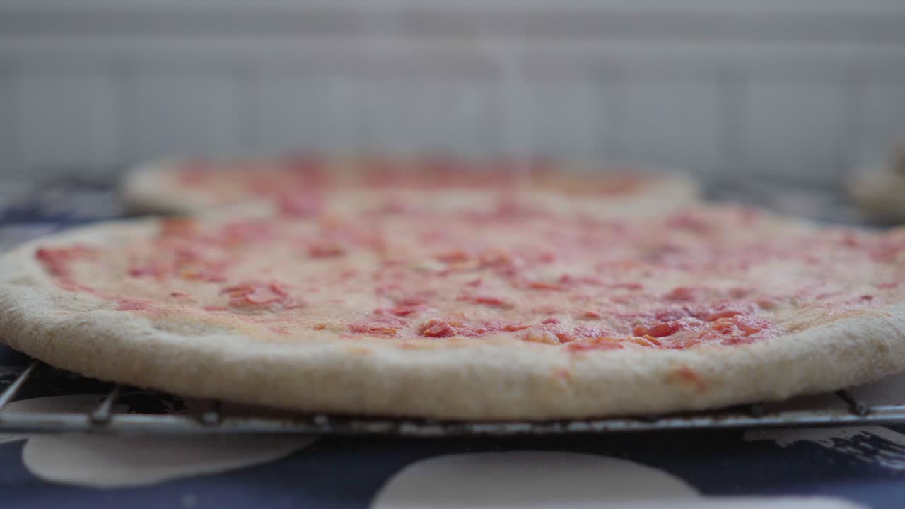 Primo piano di una pizza fatta in casa calda appena sfornata, pronta per essere condita e ultimare la cottura.