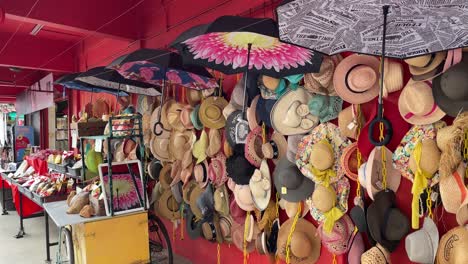 pretty-looking hats' hanging on a bright red wall outside retail shops