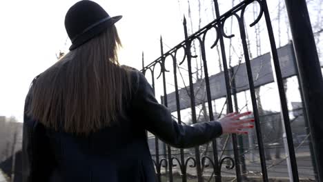 woman walking beside a fence on a sunny day