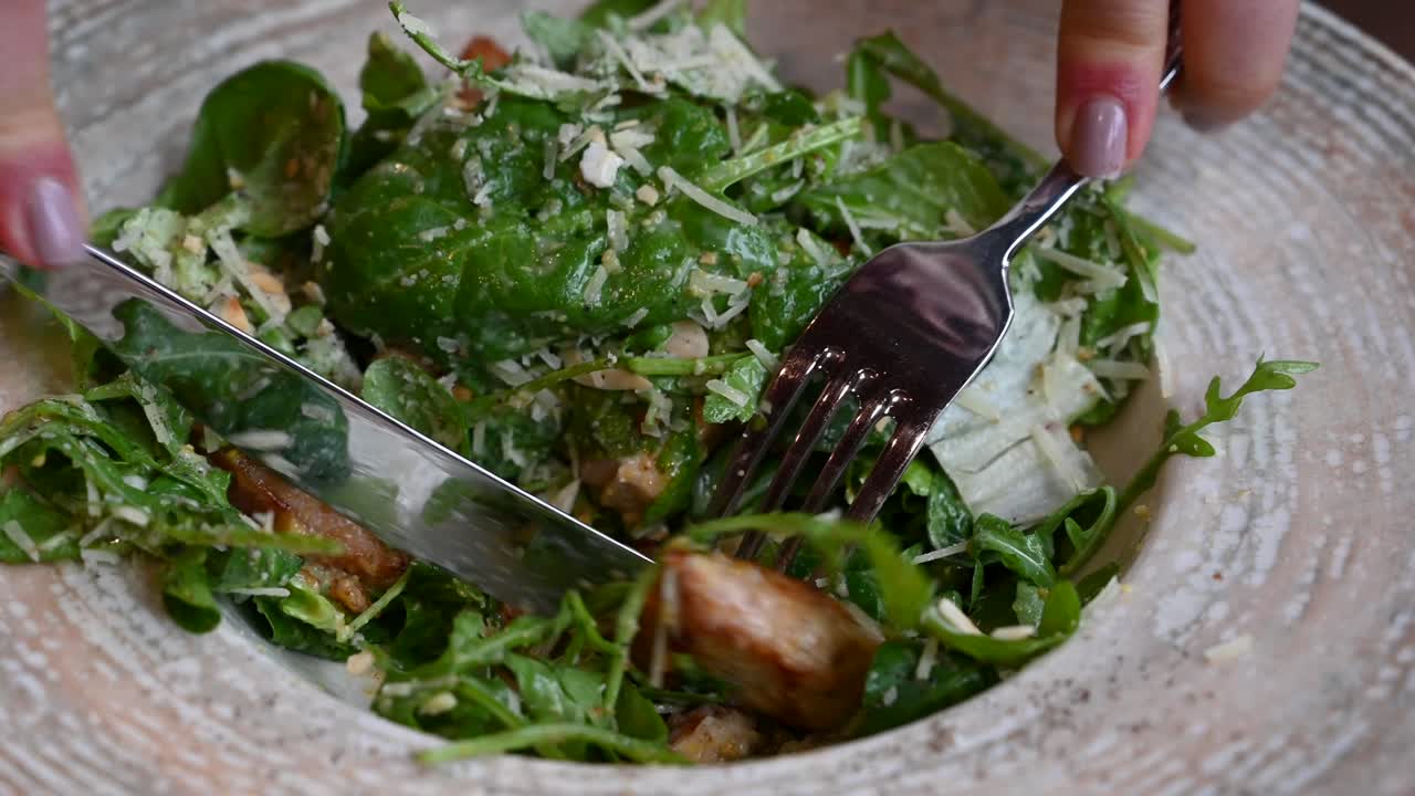 Close up of a woman eating a Caesar salad at a restaurant