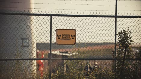 Nuclear-Radiation-Danger-Sign-on-Barbed-Wire-Perimeter-Fence-with-Contaminated-Airborne-Radioactive-Particles-in-Exclusion-Zone-Slow-Motion-4K