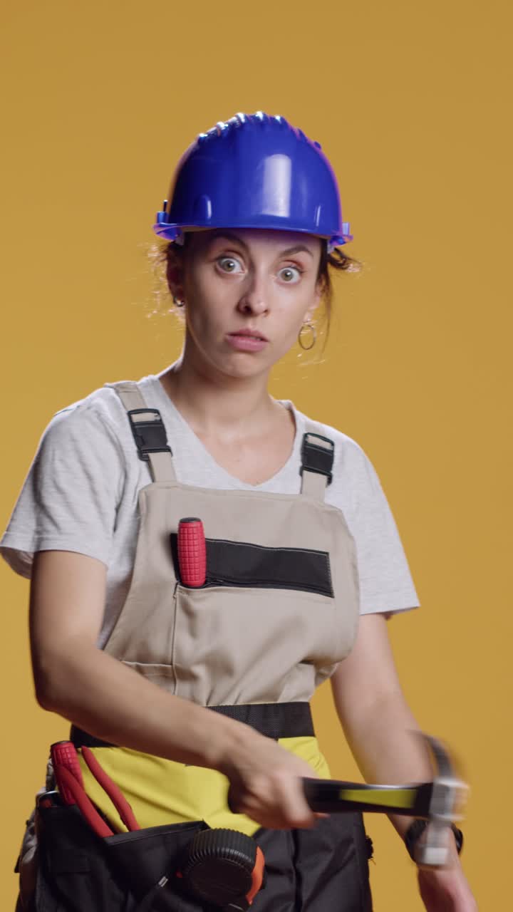 Vertical video: Portrait of empowered female builder acting dangerous with hammer